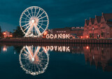 Reflection of the Ferris wheel in Gdansk, Poland. Old town center in the touristic city on the shore of the Baltic Sea in Poland. Beautiful night city lights