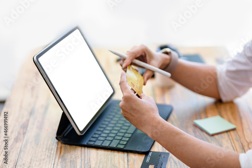 Businesswoman shopping online using a tablet blank white screen holding a credit card at the office.