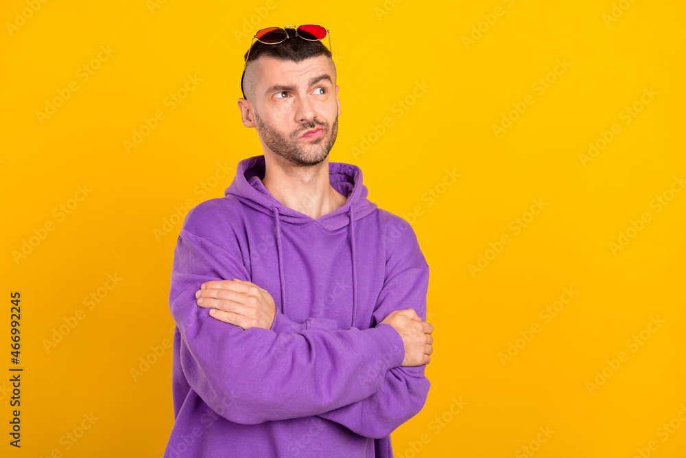 Photo of young minded curious man wear sunglass hands crossed look empty space isolated on yellow color background Photo of young minded curious man wear sunglass hands crossed look empty space isolated on yellow color background