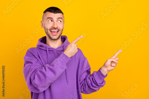 Portrait of attractive cheerful guy demonstrating recommend ad copy space isolated over bright yellow color background