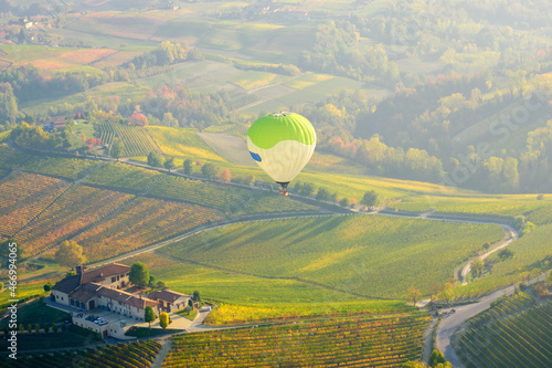 Aerostatic balloons are flying over the hills of Langhe (Piedmont, Northern Italy), covered by vineyards during fall season; UNESCO Site since 2014.