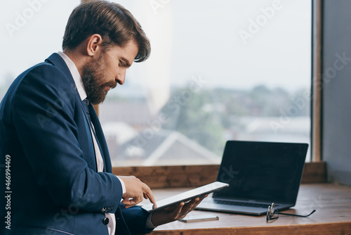 man in a suit near the window with a laptop communication