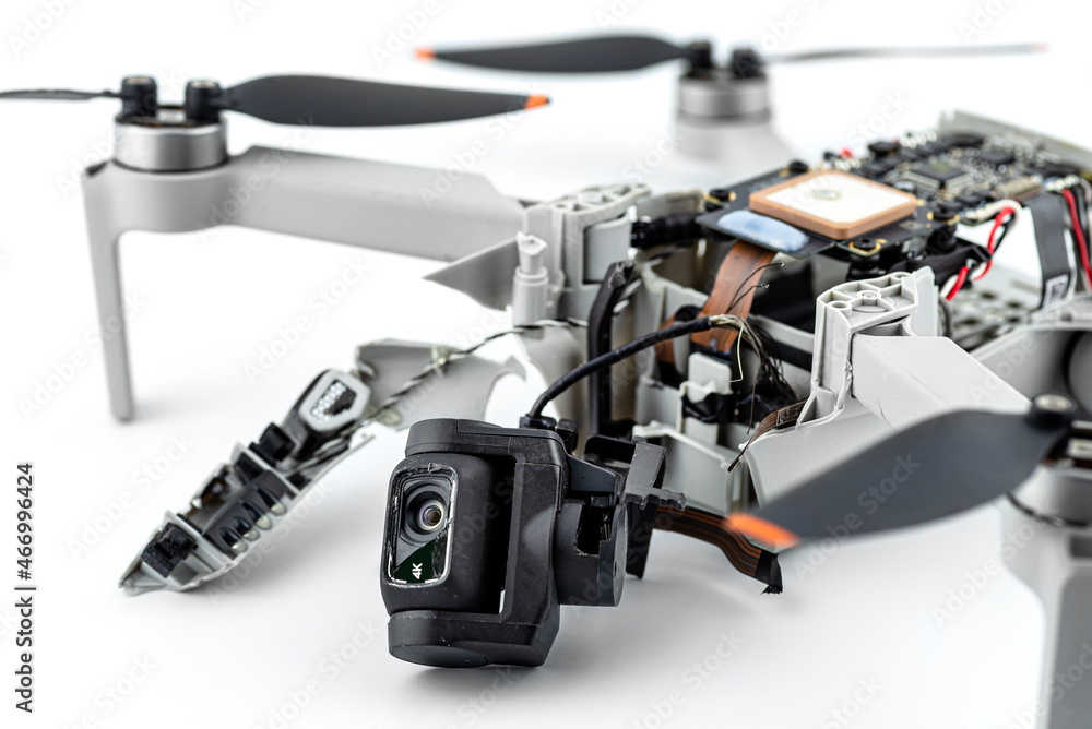 Naklejka premium A broken drone after a fall with torn cables and a broken camera, isolated on a white background.