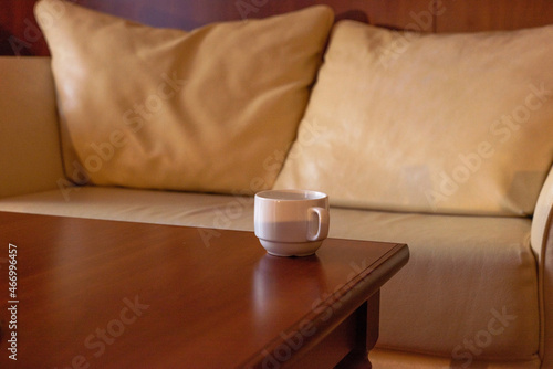 a tea cup on the table, against the background of the sofa cushions in warm colors