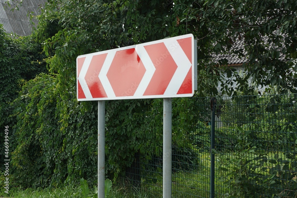 one big road sign turning direction with red white arrows in the green