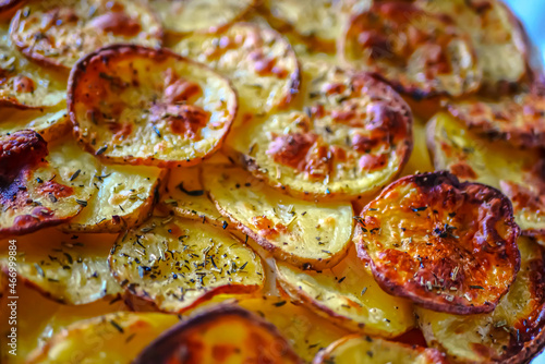 Oven baked potato slices with spices close-up. Homemade food baked appetizing potatoes background