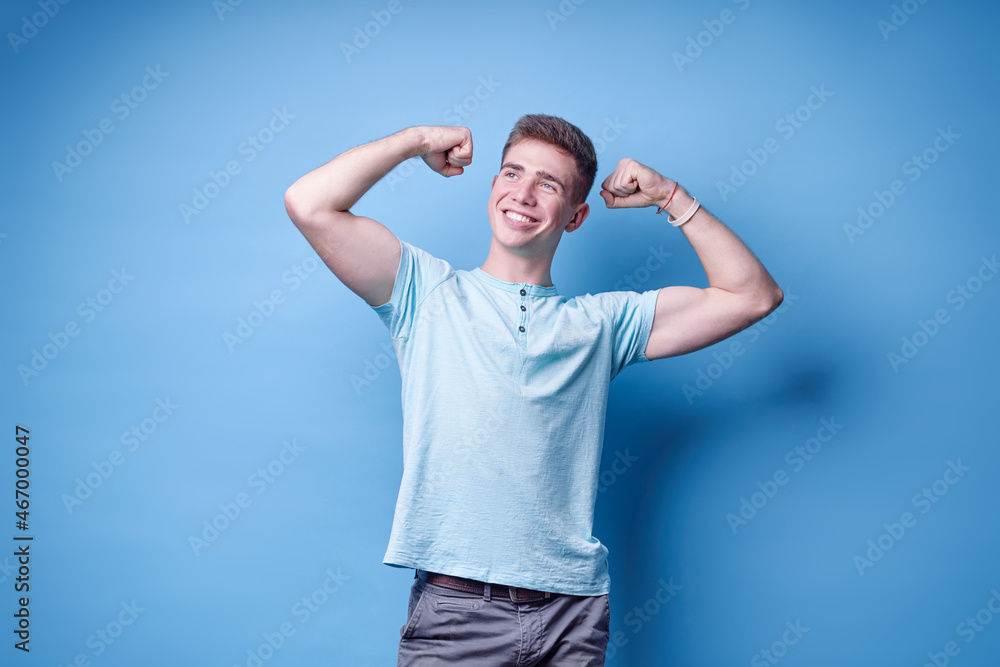 Strong and energy. Handsome young man showing bicep on his arm. Studio portrait with blue background. Strong and energy. Handsome young man showing bicep on his arm. Studio portrait with blue background.