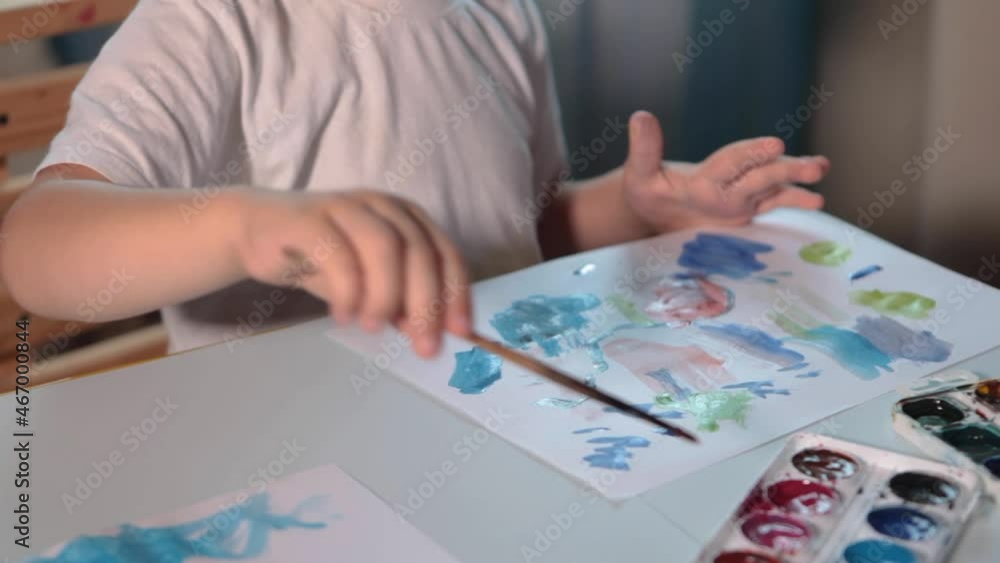 A boy draws with paints at a table in his room. High quality FullHD footageA boy draws with paints at a table in his room. A boy draws with paints at a table in his room. High quality FullHD footageA boy draws with paints at a table in his room.