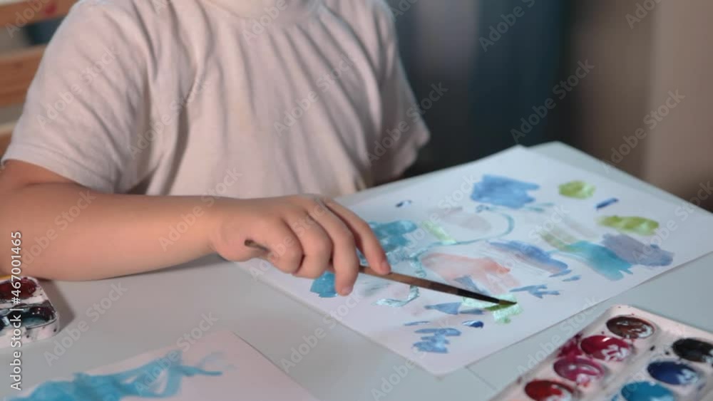 A boy draws with paints at a table in his room. High quality FullHD footageA boy draws with paints at a table in his room. A boy draws with paints at a table in his room. High quality FullHD footageA boy draws with paints at a table in his room.