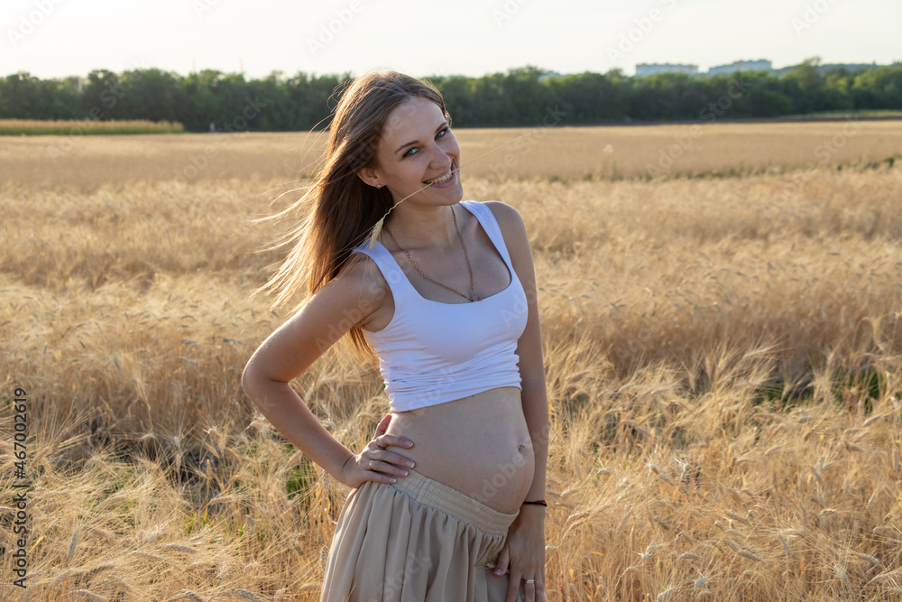 Beautiful pregnant woman with naked belly smiling in wheat field Beautiful pregnant woman with naked belly smiling in wheat field