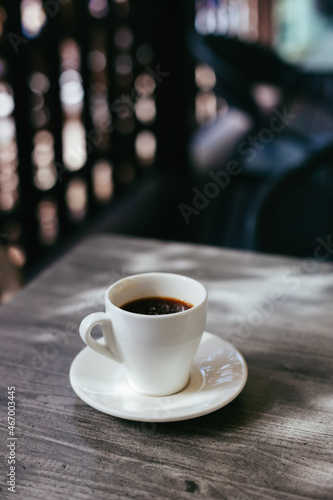 Cup of black coffee on a rustic wooden table in a street cafe.