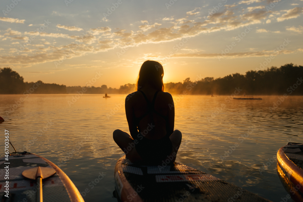 silhouette of girl on stand up paddle board, meet the rising sun