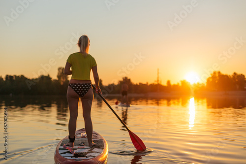SUP a young girl on stand up paddle board at sunset
