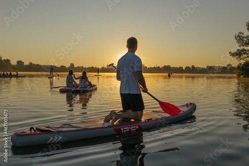 A man on a sup on the background of the river in the rays of the sunset © Oleh