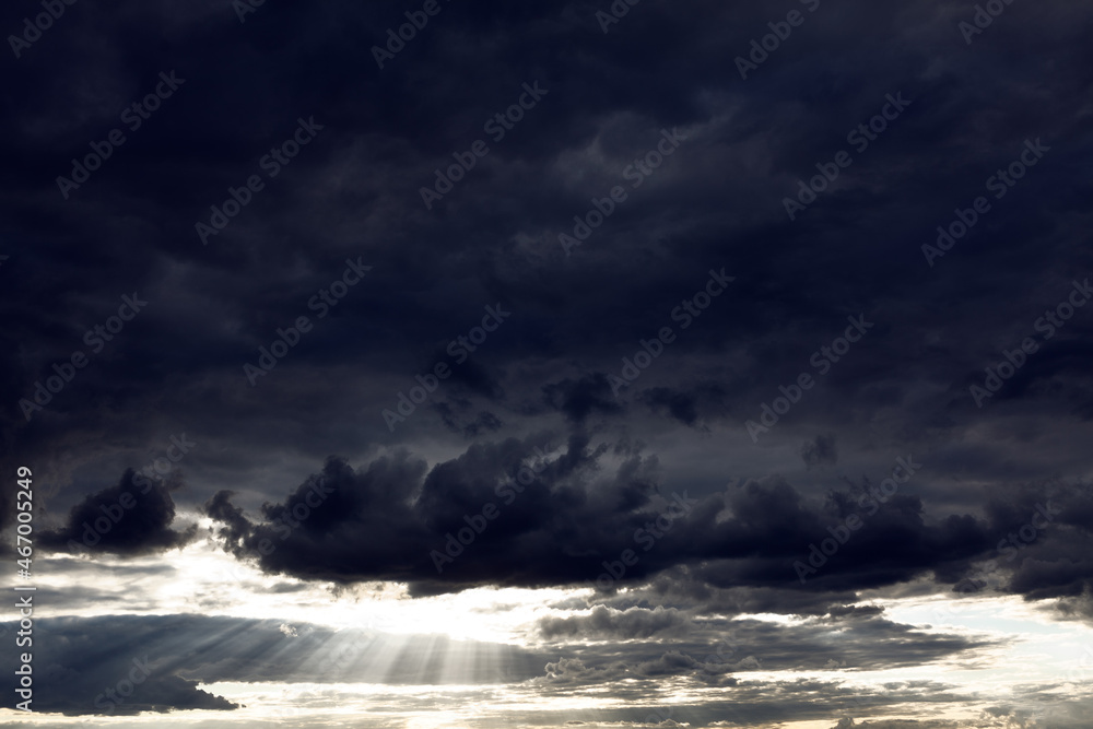 Black clouds with sun rays . Dramatic dark sky with sunlight . Epic heaven