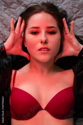 sexy brunette in red underwear and leather jacket posing in red light in dark room