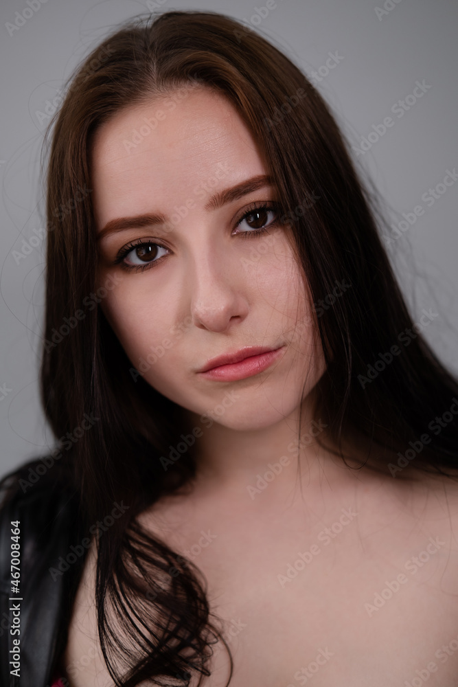 young brunette woman in black leather jacket. beautiful girl millenial on grey background. young brunette woman in black leather jacket. beautiful girl millenial on grey background.
