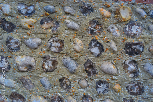 A stone wall that is common in England. A wall of large stones hidden with cement small round gray stones. photo