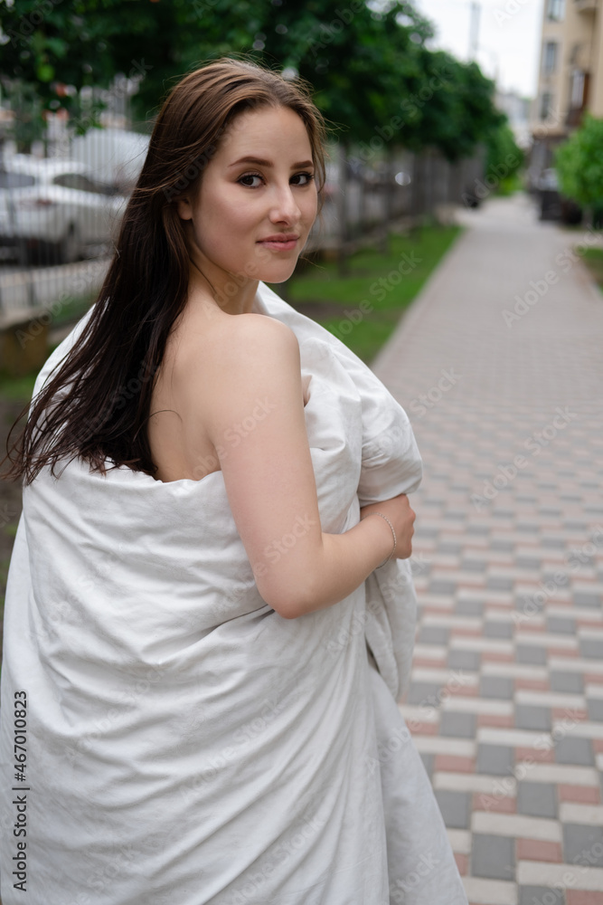 pretty girl in a white blanket walking by the street pretty girl in a white blanket walking by the street