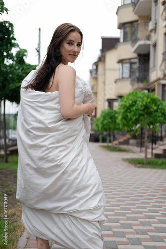 pretty girl in a white blanket walking by the street © OliaVesna