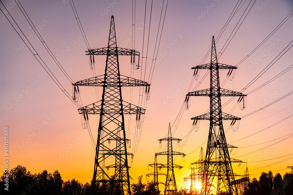 Fototapeta premium Shadows of electical high voltage towers on sunset. Dark electricity power silhouettes.