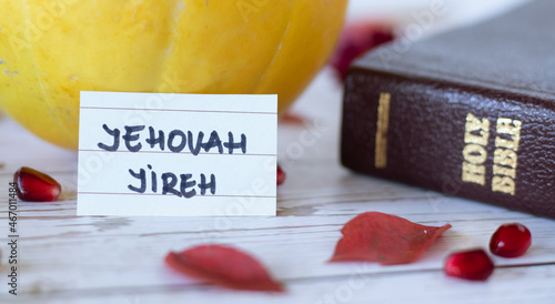 Jehovah Jireh, a handwritten name of God with Holy Bible book, pumpkin, and fall red leaves. The biblical concept of love. A Christian faith that the LORD will provide for us. A closeup. photo