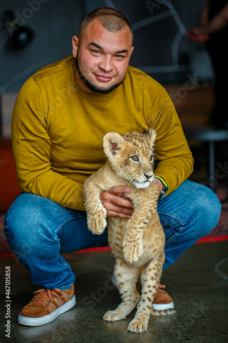 Obraz na płótnie Man playing with a young lion cub in the room w salonie