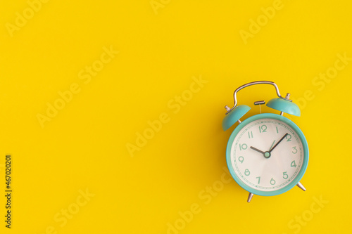 Blue alarm clock on yellow background. Top view with copy space. Flat lay. Back to school concept.