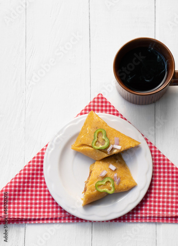 Homemade tamale served with a cup of coffee on a white table.