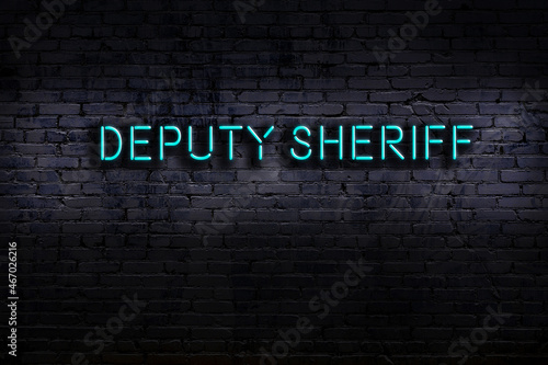 Night view of neon sign on brick wall with inscription deputy sheriff photo