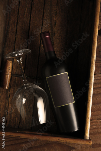 Wine Still Life: Flat lay wine bottle wineglass and corkscrew in a wood box with warm side light. Vertical format with copy space. © Steve Cukrov