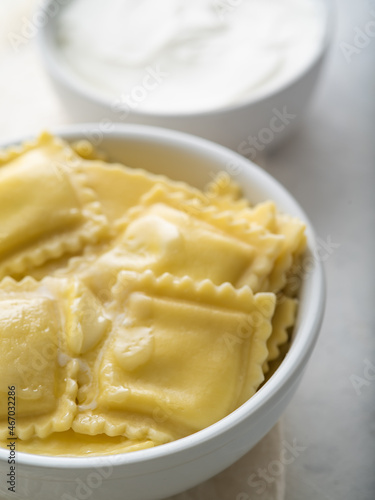 Delicious Italian ravioli and sour cream sauce. Macro photography. White background. Pastel shades. Food design, restaurant, hotel, cafe, cookbook, culinary blog.