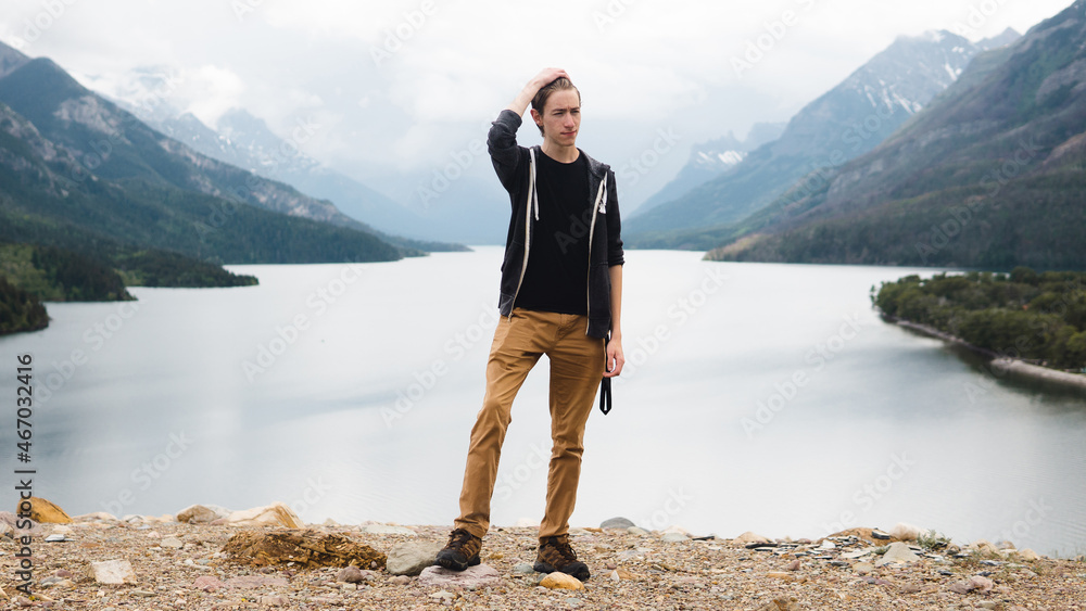 man posing in front of a beautiful lake and mountains