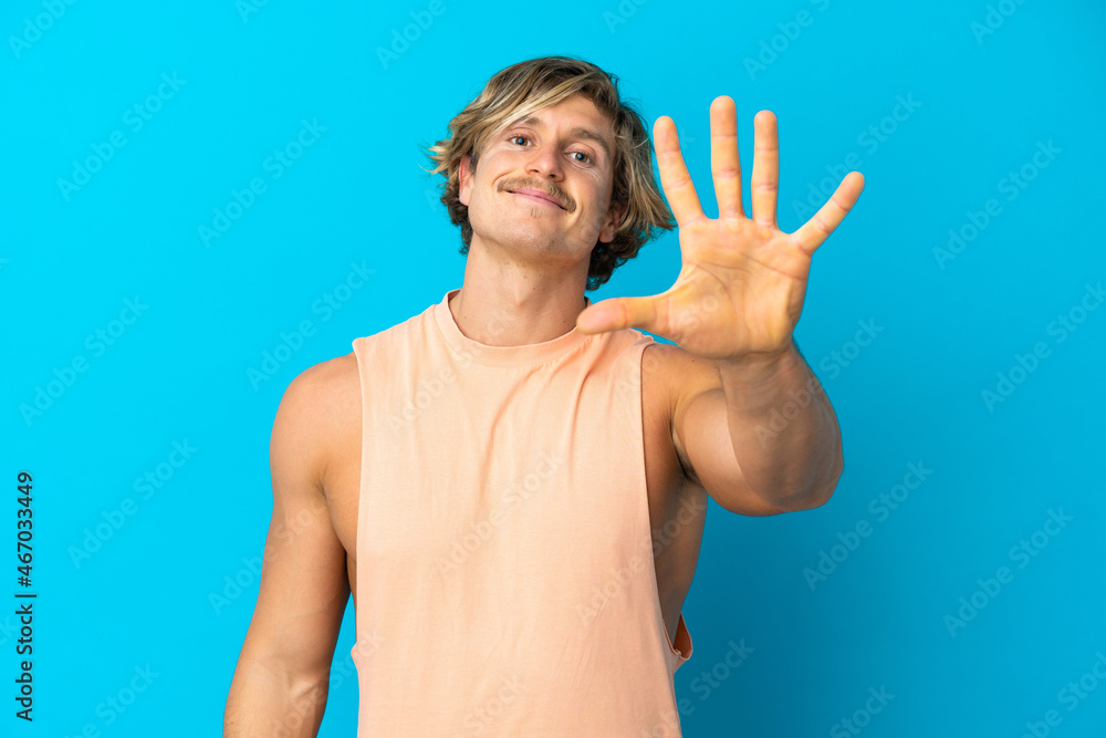 Naklejka premium Handsome blonde man isolated on blue background counting five with fingers