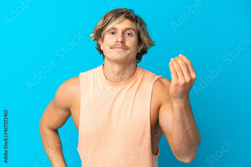 Handsome blonde man isolated on blue background making Italian gesture