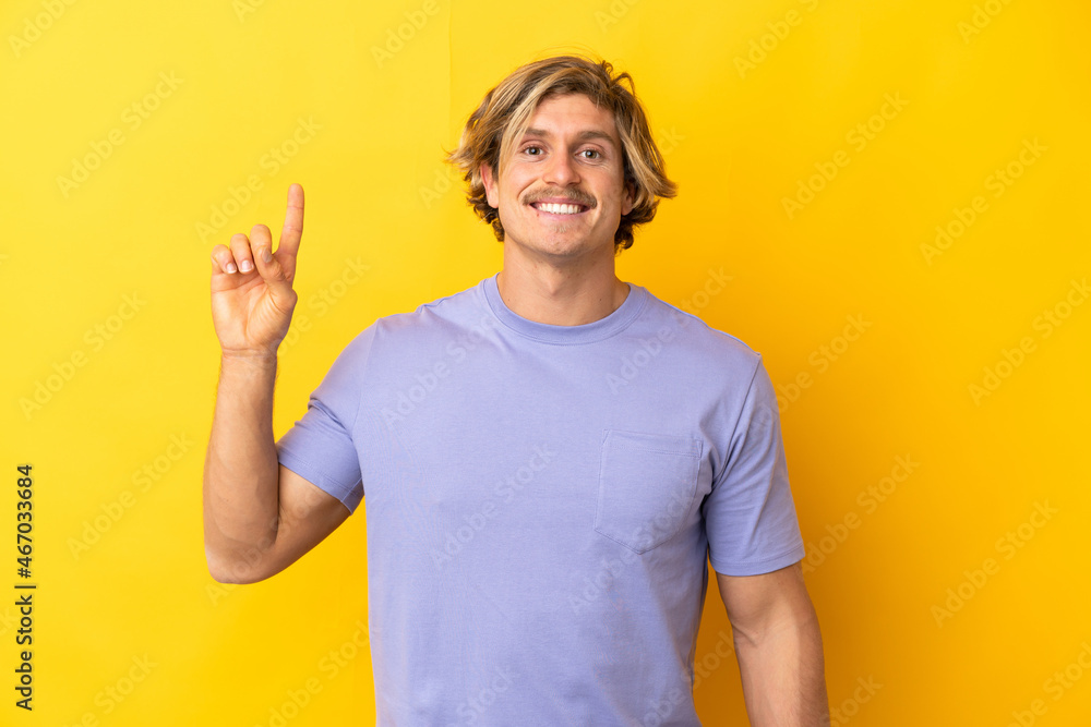 Handsome blonde man isolated on yellow background pointing up a great idea Handsome blonde man isolated on yellow background pointing up a great idea