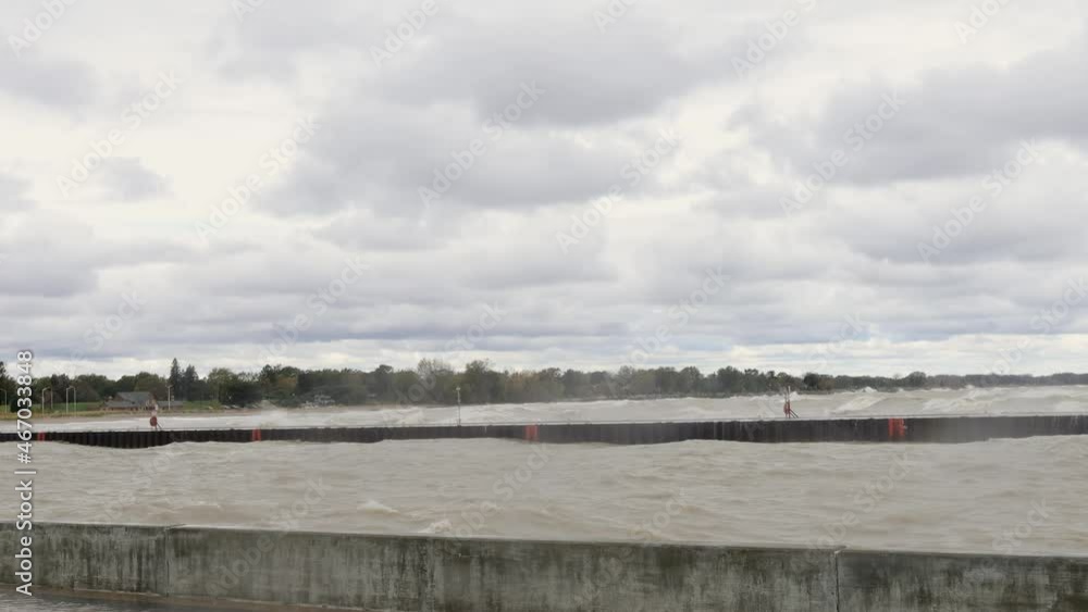 Rough waves washing into the shoreline off Lake Michigan. Waves washing over pier. Concrete barrier holding water back. Misty waves from the wind. Rough waves washing into the shoreline off Lake Michigan. Waves washing over pier. Concrete barrier holding water back. Misty waves from the wind.