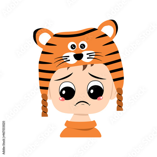 Boy with big eyes and depressive emotion, crying, tears face in tiger hat. Cute kid with sad face in a festive costume for New Year, Christmas and holiday. Head of adorable child with emotions