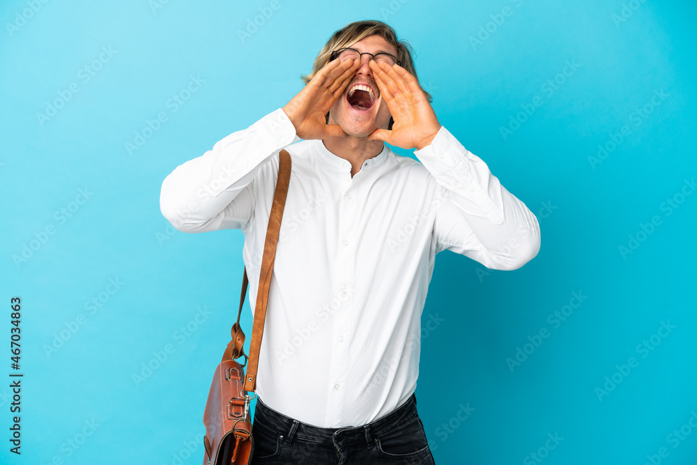 Young blonde businessman isolated on blue background shouting and announcing something Young blonde businessman isolated on blue background shouting and announcing something