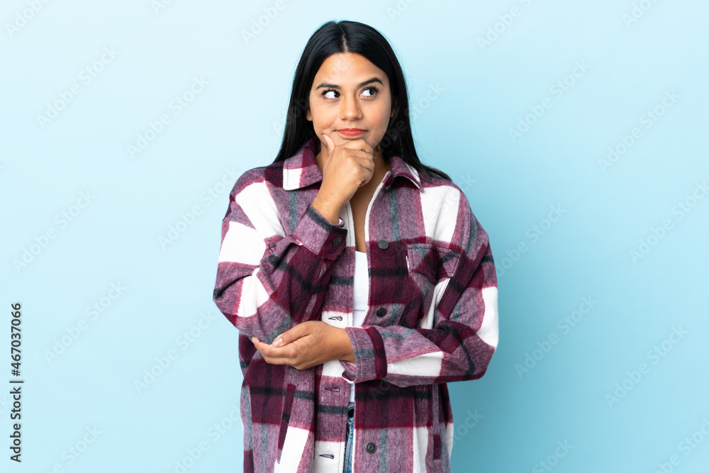 Young latin woman woman isolated on blue background thinking an idea while looking up Young latin woman woman isolated on blue background thinking an idea while looking up