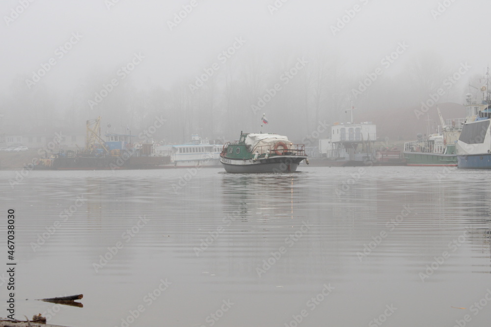Fototapeta premium the boat sails into the river port in fog