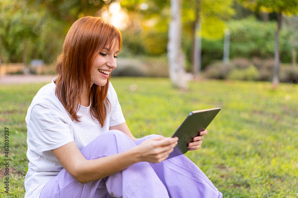 Young pretty redhead woman at outdoors holding a tablet Young pretty redhead woman at outdoors holding a tablet