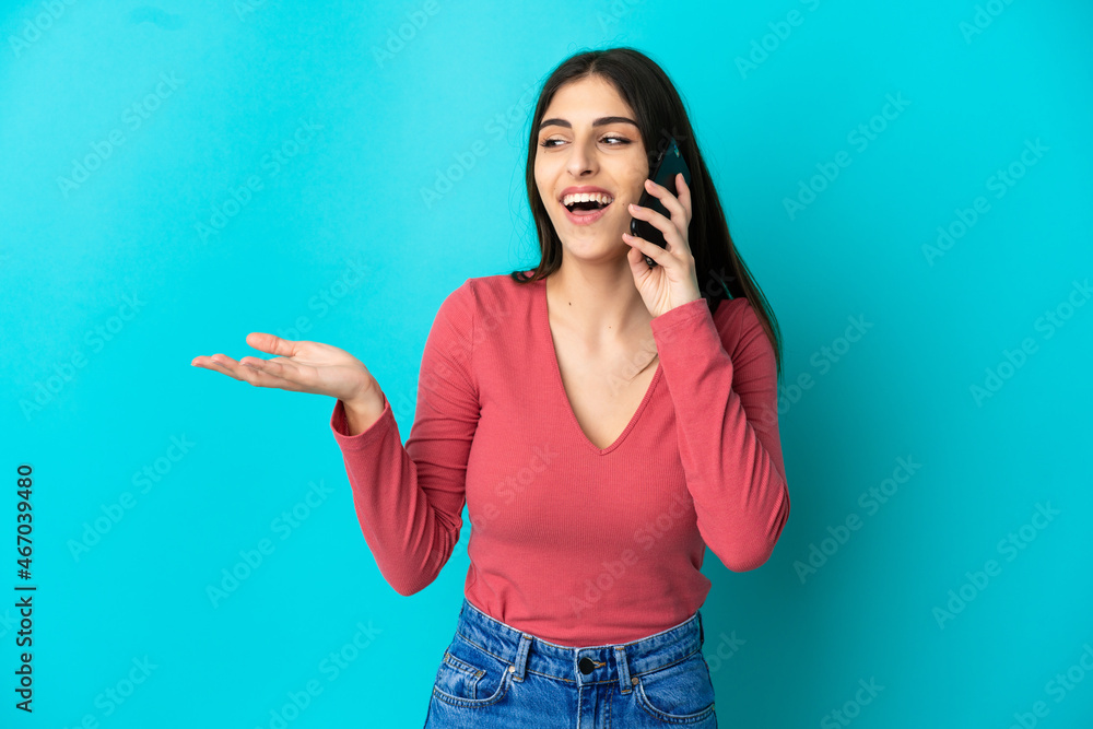 Young caucasian woman isolated on blue background keeping a conversation with the mobile phone with someone Young caucasian woman isolated on blue background keeping a conversation with the mobile phone with someone