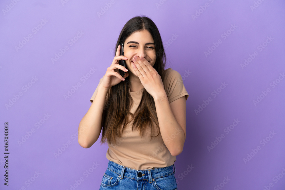 Young caucasian woman using mobile phone isolated on purple background happy and smiling covering mouth with hand Young caucasian woman using mobile phone isolated on purple background happy and smiling covering mouth with hand