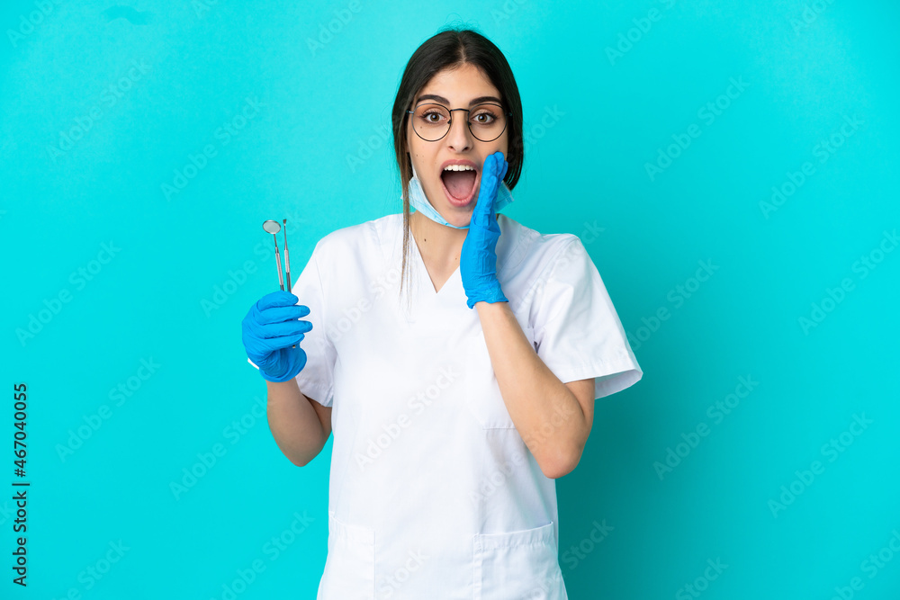 Young caucasian dentist woman holding tools isolated on blue background with surprise and shocked facial expression Young caucasian dentist woman holding tools isolated on blue background with surprise and shocked facial expression