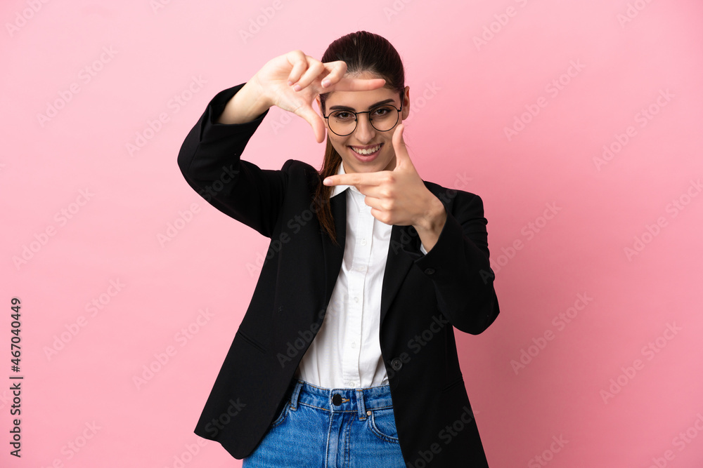 Young caucasian business woman isolated on pink background focusing face. Framing symbol Young caucasian business woman isolated on pink background focusing face. Framing symbol