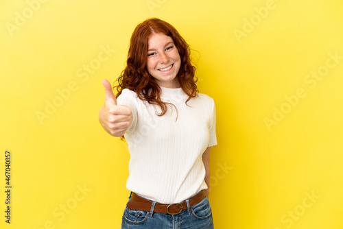 Teenager reddish woman isolated on yellow background with thumbs up because something good has happened
