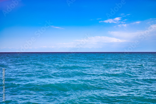 Seascape with clear horizon line and clouds on blue sky. Travel background and banner. Ocean waves.