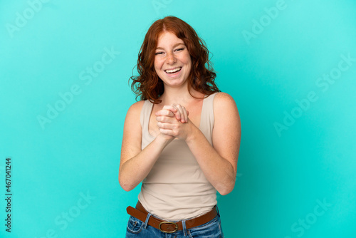 Teenager reddish woman isolated on blue background laughing