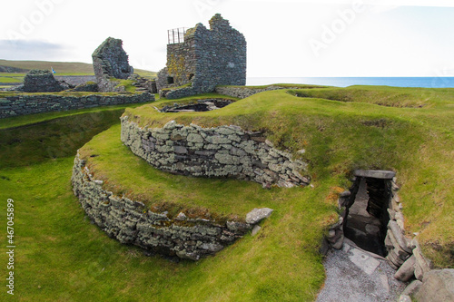 Iron Age wheelhouse in front of Laird's House at the Jarlshof Prehistoric and Norse settlement in the Shetland Islands, Scotland, near the North Sea photo